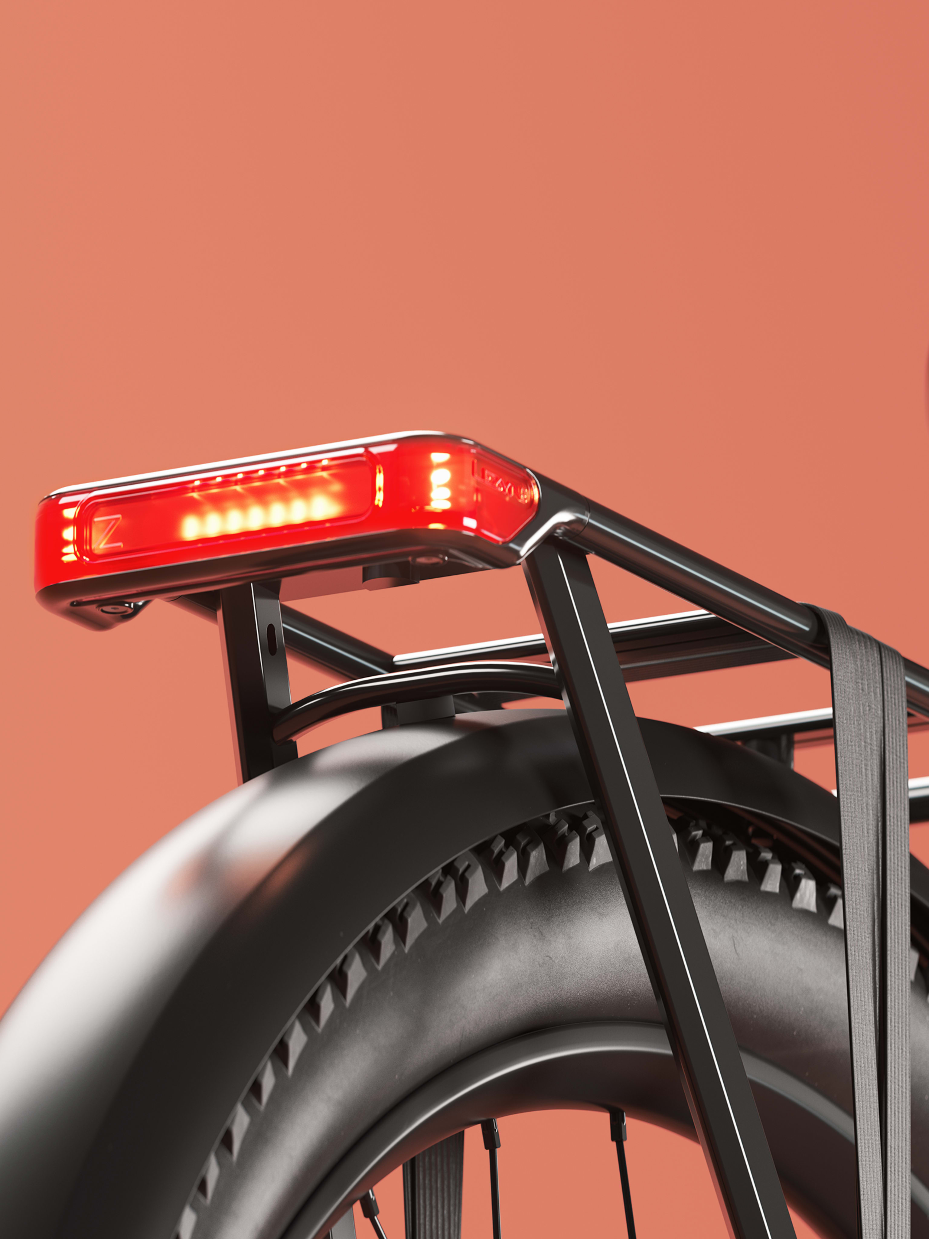 Close-up of a black bicycle’s rear section showing the tire, fender, rear rack, and illuminated red taillight against an orange background.