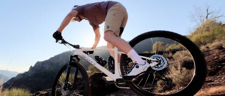 Mountain biker riding downhill in mountainous terrain. 