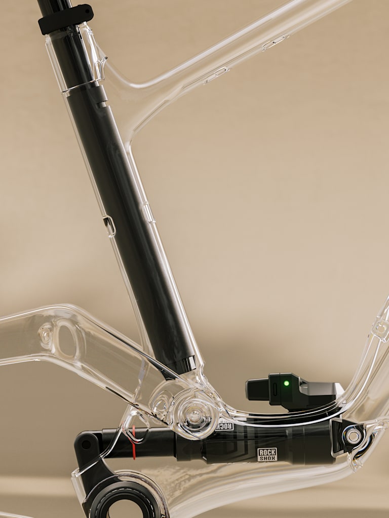 A transparent bicycle frame with internal components is set against a soft, neutral background.