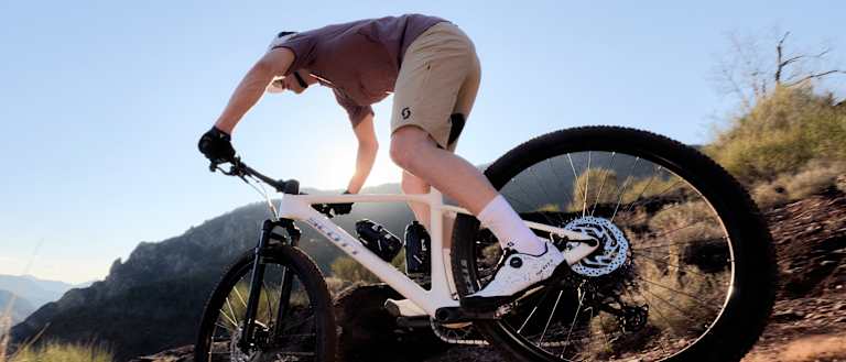 Mountain biker riding downhill in mountainous terrain.