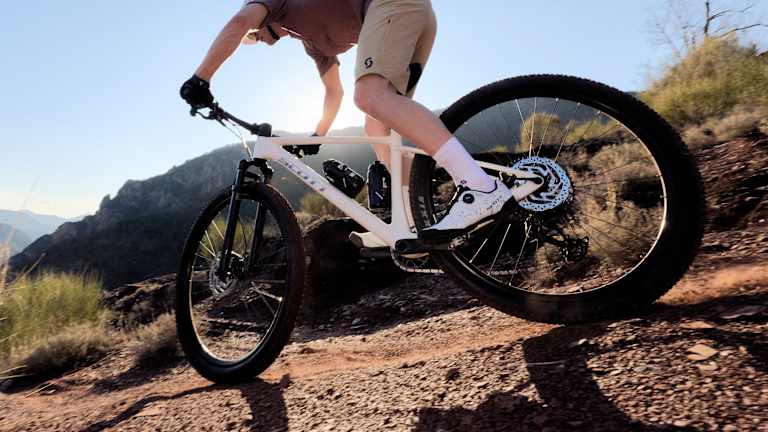 Mountain biker riding downhill in mountainous terrain.