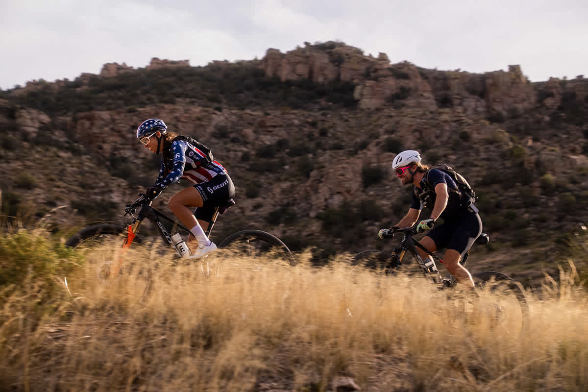 Hannah Otto and Ryan Standish riding through golden desert grass at dusk