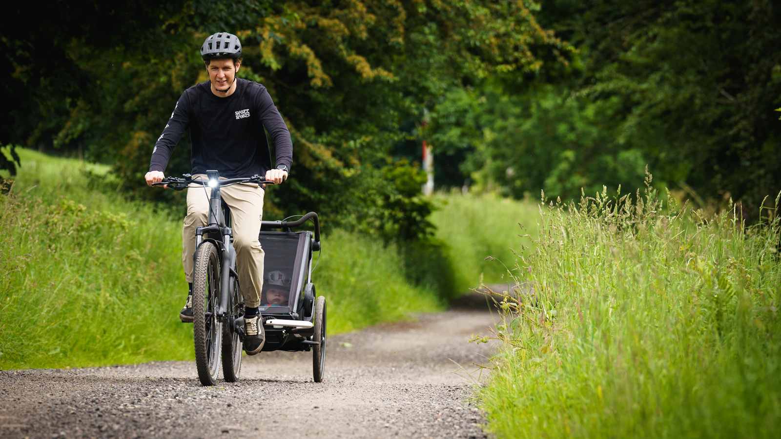 A man cycling with a trailer attached, showcasing a practical mode of transportation for carrying goods.